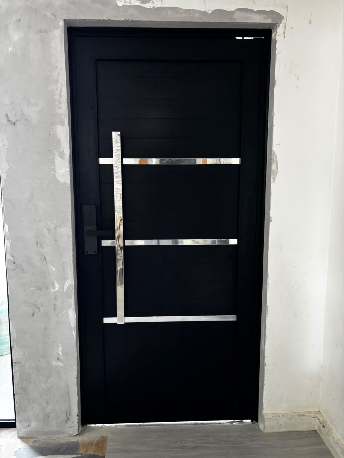 Porta de entrada preta com frisos em inox